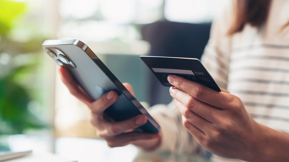 woman holding credit card and phone